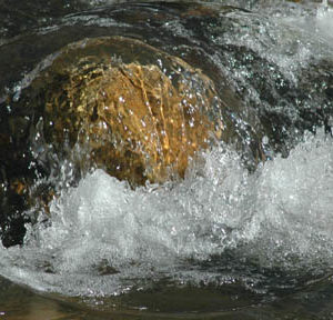 Cycle photo of water flowing over a rock .
